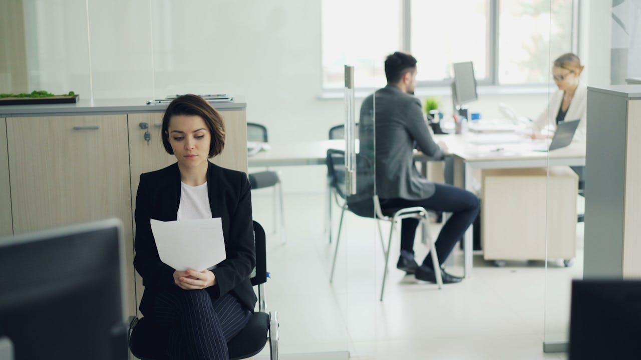 Business professionals working in a modern office setting with focus on a seated woman.