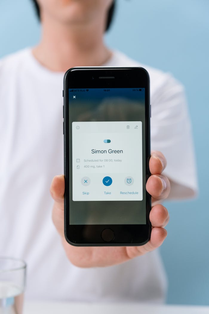 Close-up of a smartphone displaying a medication reminder app held by a faceless person.
